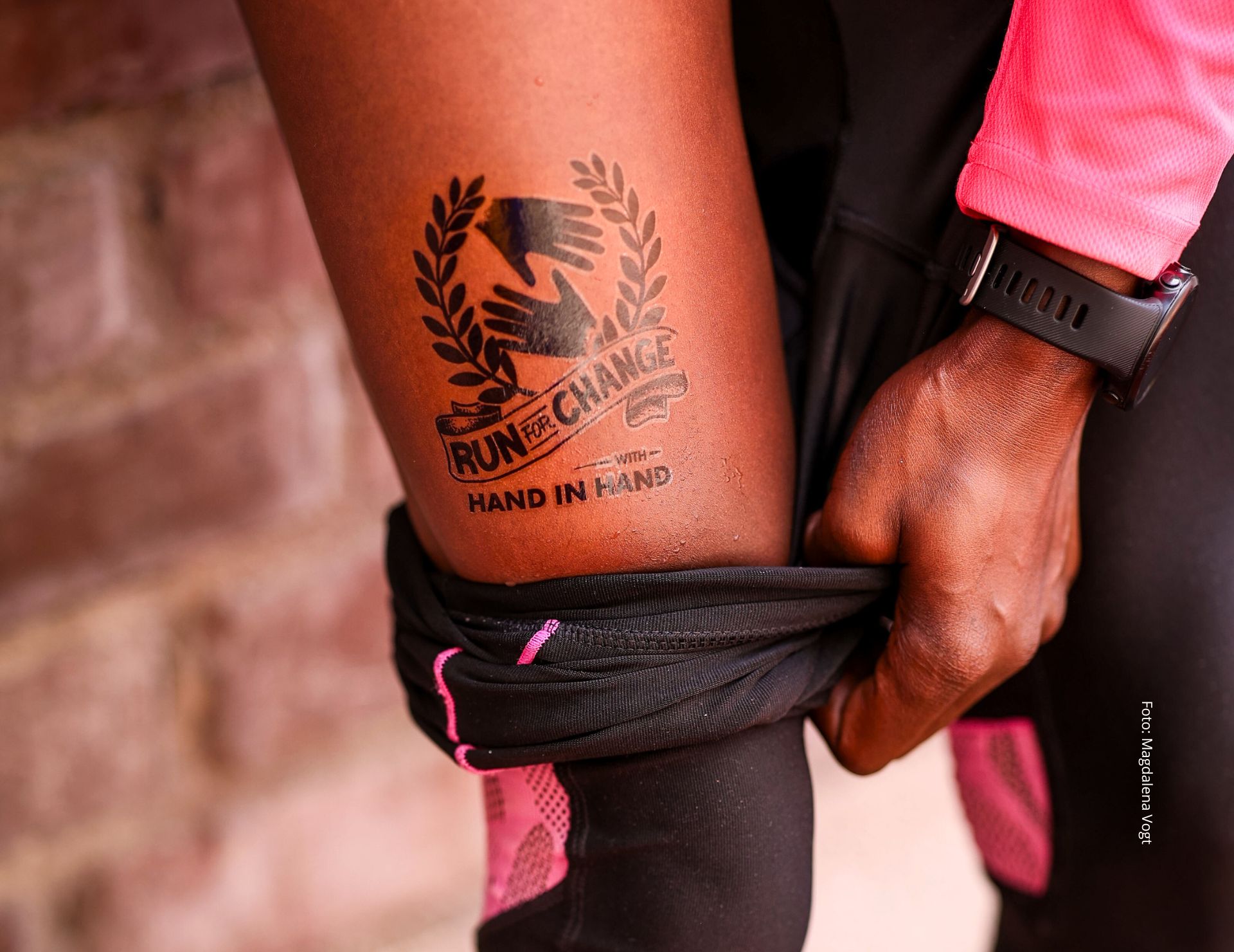 Löpare visar upp sin tatuering med texten "Run for Change" och "Hand in Hand".